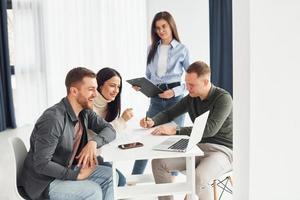 Four people works in the office by sitting by the table indoors photo