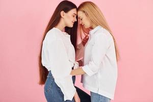 Embracing each other. Young mother with her daughter standing in the studio photo