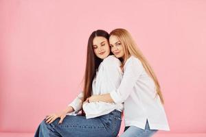 sobre fondo rosa. joven madre con su hija de pie en el estudio foto