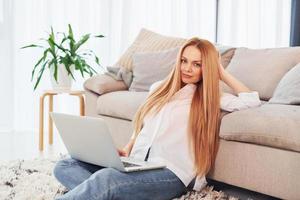 mujer joven en camisa blanca y jeans está en casa foto