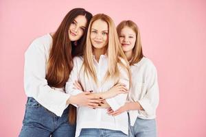 posando para una cámara. la joven madre con sus dos hijas está en el estudio foto