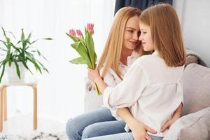 feliz día de la madre. mujer joven con su hija está en casa durante el día foto