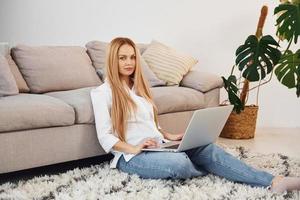 Working from home. Young woman in white shirt and jeans indoors photo