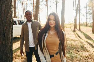 Bus is behind. Young couple is traveling in the forest at daytime together photo