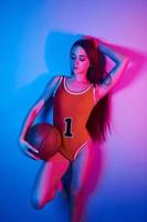 Sexy body. Fashionable young woman standing in the studio with neon light photo