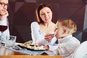Young guy, woman and little boy. Indoors of new modern luxury restaurant photo