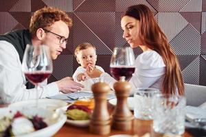 Young guy, woman and little boy. Indoors of new modern luxury restaurant photo