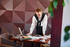 Man standing by table with laptop and documents. Indoors of new modern luxury restaurant photo