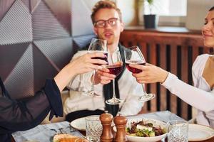 Cheering with glasses of wine. Indoors of new modern luxury restaurant photo