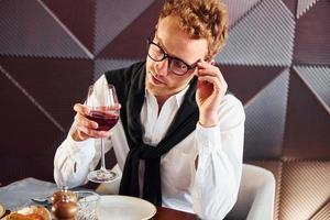 Man in glasses sits by the table. Indoors of new modern luxury restaurant photo