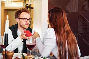 Young guy makes proposal to a woman. Indoors of new modern luxury restaurant photo