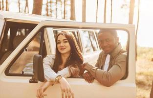 cerca del autobús blanco. una pareja joven viaja juntos por el bosque durante el día foto