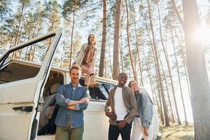 Destination place. Group of young people is traveling together in the forest at daytime photo