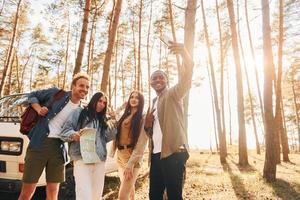 Making selfie. Group of young people is traveling together in the forest at daytime photo