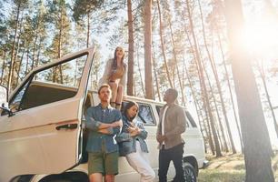 Destination place. Group of young people is traveling together in the forest at daytime photo