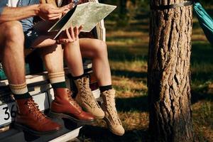 Sitting on the back of the car. Young couple is traveling in the forest at daytime together photo