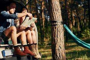 Weekend activities. Young couple is traveling in the forest at daytime together photo