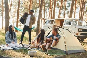 Camp and car. Group of young people is traveling together in the forest at daytime photo