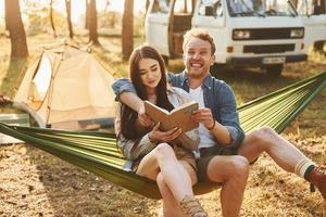 Holding book. Young couple is traveling in the forest at daytime together photo