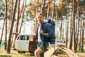 Looks at location. Man is traveling alone in the forest at daytime at summer photo