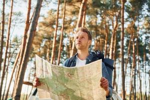 utiliza el mapa. el hombre viaja solo en el bosque durante el día en verano foto