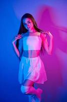 en falda joven de moda parada en el estudio con luz de neón foto