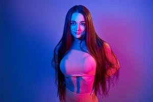 Fitness body type. Fashionable young woman standing in the studio with neon light photo