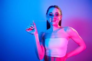 emociones positivas. joven de moda parada en el estudio con luz de neón foto