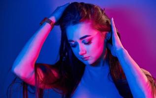 Portrait of fashionable young woman that standing in the studio with neon light photo