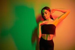 colores verde y rojo. joven de moda parada en el estudio con luz de neón foto