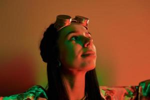 Retro eyewear. Fashionable young woman standing in the studio with neon light photo