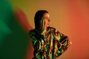 Posing for camera. Fashionable young woman standing in the studio with neon light photo