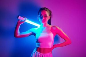 estilo futurista. joven de moda parada en el estudio con luz de neón foto