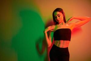 Green and red colors. Fashionable young woman standing in the studio with neon light photo