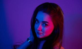 Portrait of fashionable young woman that standing in the studio with neon light photo