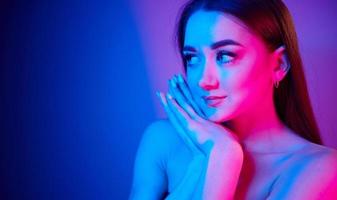 Close up view. Fashionable young woman standing in the studio with neon light photo