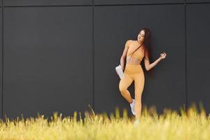 con botella de agua. mujer joven en ropa deportiva tiene sesión de fitness al aire libre foto