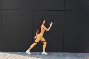 utiliza cinta de estiramiento. mujer joven en ropa deportiva tiene sesión de fitness al aire libre foto