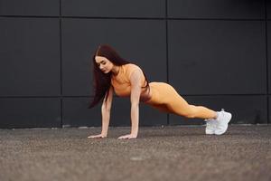 Doing push ups. Young woman in sportswear have fitness session outdoors photo