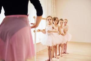 Coach teaches children. Little ballerinas preparing for performance by practicing dance moves photo