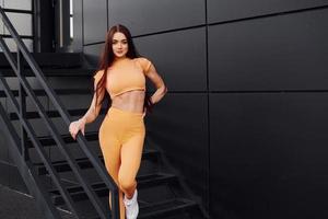 Standing on the stairs. Young woman in sportswear have fitness session outdoors photo