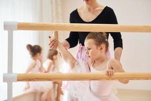 apoyado en el soporte de madera. pequeñas bailarinas preparándose para la actuación foto