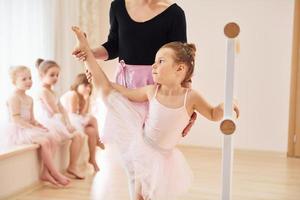 Leaning on the wooden stand. Little ballerinas preparing for performance photo