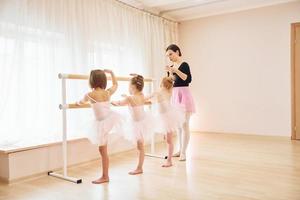 la mujer enseña movimientos de baile. pequeñas bailarinas preparándose para la actuación foto