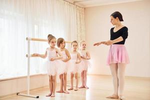 entrenador enseña a los niños. pequeñas bailarinas preparándose para la actuación practicando movimientos de baile foto