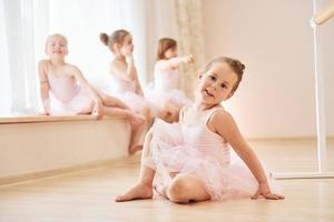 las niñas se sientan en el alféizar de la ventana y en el suelo. pequeñas bailarinas preparándose para la actuación foto