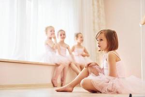 las niñas se sientan en el alféizar de la ventana y en el suelo. pequeñas bailarinas preparándose para la actuación foto