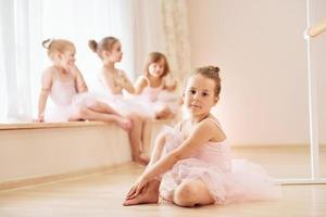 Girls sits on windowsill and on the floor. Little ballerinas preparing for performance photo