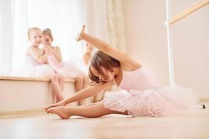 practicando en el suelo. pequeñas bailarinas preparándose para la actuación foto