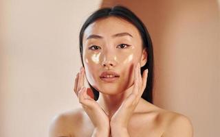 Skin cleaning. Young serious asian woman standing indoors photo